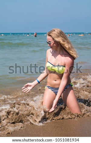 Blond teenager girl on the beach near sea or ocean
