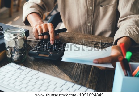 asian man working with calculator to calculate numbers. expenses calculator, payments costs with paper notes, payments table. Financial and Installment payment concept. Saving concept
 Royalty-Free Stock Photo #1051094849