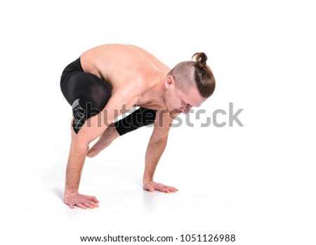 A young strong man doing yoga exercises - handstand. Studio shot over white background and white floor