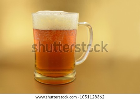 Beer glass with handle stock images. Glass with beer on a golden background. Beer on a golden background with copy space for text. Festive golden background