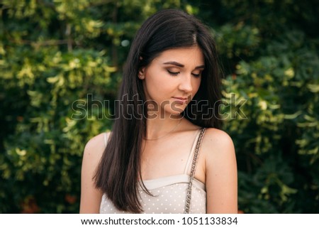 Brunette girl with makeup is standing in front of green background