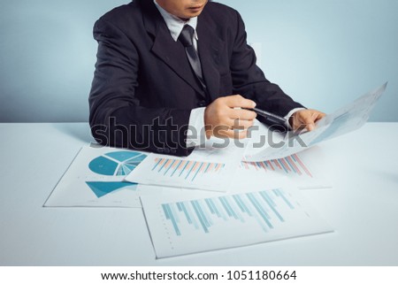 business man point a document report, show a graph on table a pen on hand 
