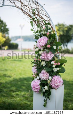 Part of wedding arch decorated with pink fresh cutted hyndrangea and creamy roses with the lake at background