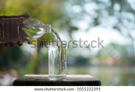 Pour a glass of water from a plastic bottle, on a natural background, in a dark light,Clean water for drinking.