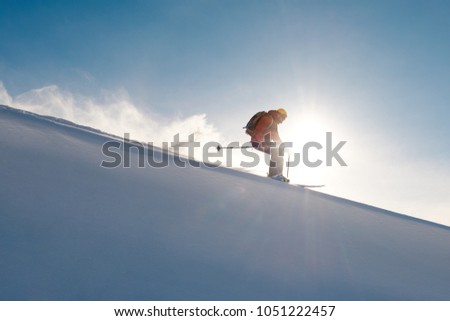 skier rides freeride on powder of snow leaving wave on sky background