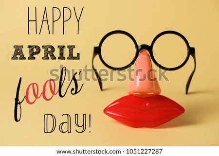 a pair of fake eyeglasses, with nose and mouth, and the text happy april fools day, on a yellow background