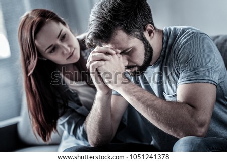 New problem. Deep upset unshaken man sitting in the room near his wife supporting head by hands closing eyes. Royalty-Free Stock Photo #1051241378