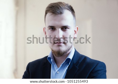 Beautiful handsome young business man at coworking office room with white brick background.