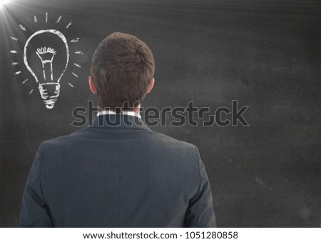 Digital composite of Back of Business man with light bulb doodle and flare against grey wall