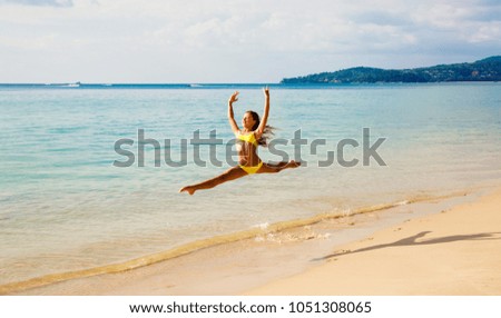 The beautiful, young woman dances the ballet on the seashore, in a jump, the gymnast