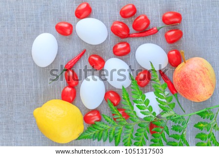 Easter composition, eggs, tomatoes, chilli pepper, apple and lemon on the textured background. Vegetables and fruits in Eastern composition picture. Colorful Eastern composition. Best Easter picture.