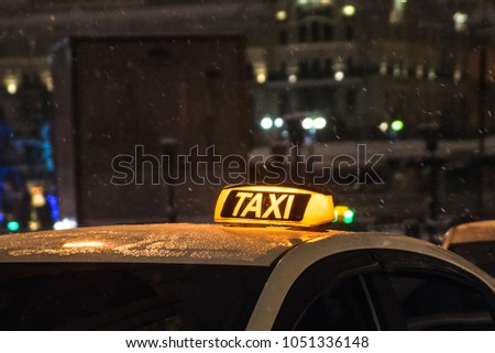 Illuminated taxi sign on the roof of a taxi at night city