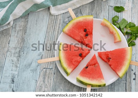 Watermelon slice popsicles on a wooden background