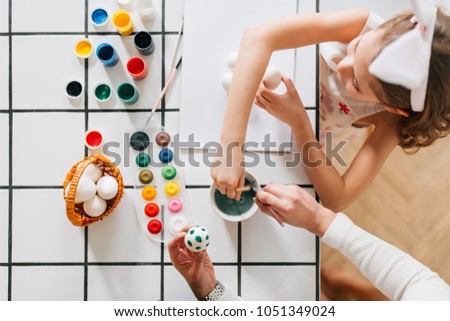 Top view of mother and little girl painting easter eggs together 