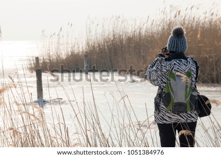 Woman in cap photographs in the winter lake. Neusiedler See, Austria. 