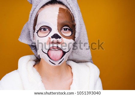 funny young girl with a towel on her head showing tongue, on face mask with a picture of muzzle of a dog