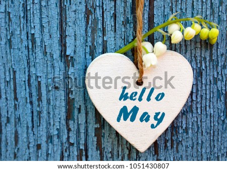 Hello May greeting card with decorative white heart and lily of the valley flower on old blue wooden background.
Springtime concept.Selective focus.
