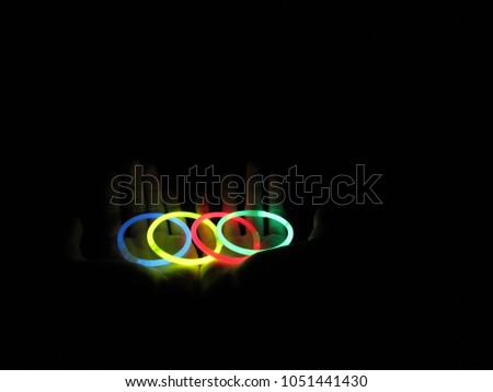 four blue phosphorescent yellow and red bracelets on hands