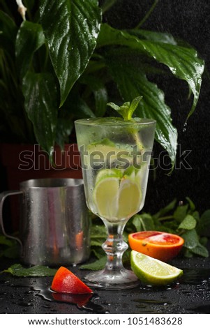 lemonade with orange in a glass on a dark background. spray and motion