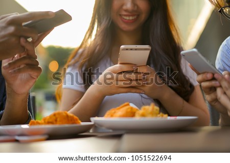 close up on young asian woman using smartphone for take a photo on fried chicken with friend at outdoor restaurant in weekend , people lifestyle concept