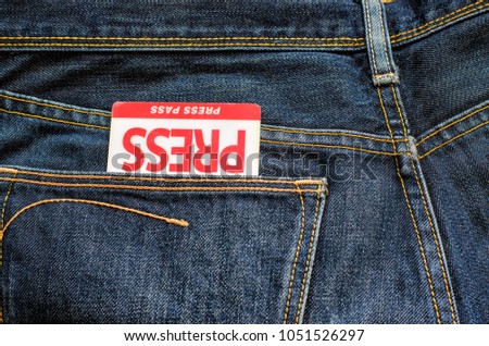 Journalist's certificate (press pass, media representative), nested upside down in the back pocket of a dark blue worn jeans, background, close-up