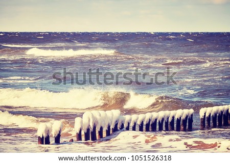 Frozen wooden breakwater on a windy day, color toned picture, Baltic Sea in Poland.
