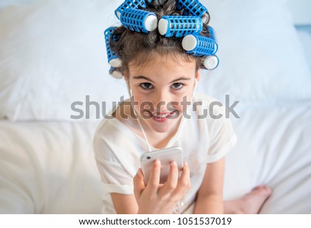 little girl posing with curlers and Smartphone, surprised and happy