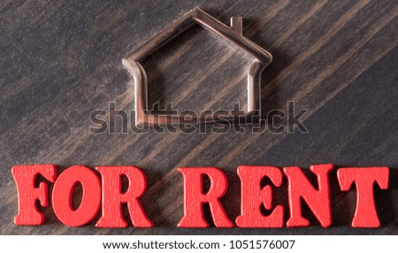 FOR RENT words with metal house symbol on wooden table top