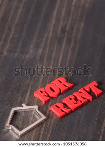 FOR RENT words with metal house symbol on wooden table top