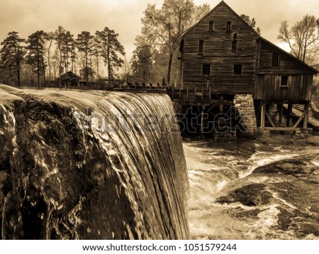 Vintage or antique filter with brown tones of the raging waterfall after a rain at the old gristmill at Yates Mill County Park in Raleigh North Carolina, Triangle area, Wake County.