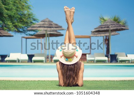 Young woman lying by the swimming pool enjoying tanning