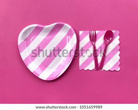 Closeup pink & white stripe printed paper plate and napkin with plastic spoon & fork on pastel pink background. The concept of Love party,Valentine day,wedding celebration,anniversary.Selective focus.