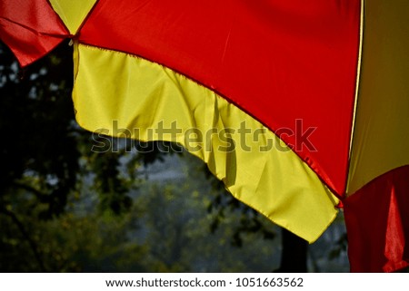 Red & yellow clothes of a large umbrella isolated unique stock photograph