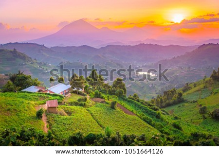 Kisoro Uganda beautiful sunset over mountains and hills of pastures and farms in villages of Uganda. Amazing colorful sky and incredible landscape to travel and admire the beauty of nature in Africa Royalty-Free Stock Photo #1051664126