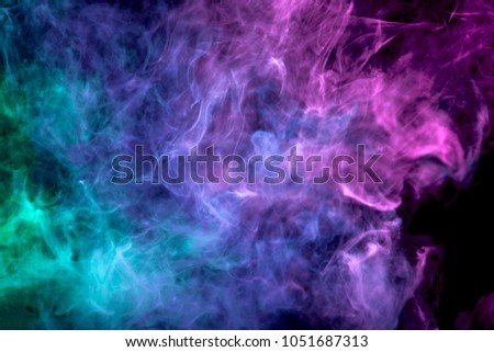 Dense multicolored smoke of pink, blue and purple colors on a black isolated background. Background of smoke vape