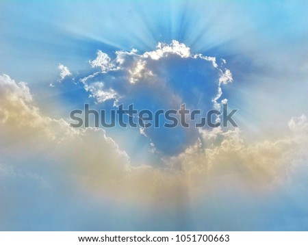 The sky with the sun shines under the shadow of a beautiful cloud.