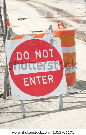 Close up on a Do Not Enter Sign beside an orange street cone, along a closed road at a construction site 