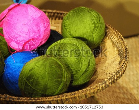 Green, pink and blue color thread For sewing put in a basket.