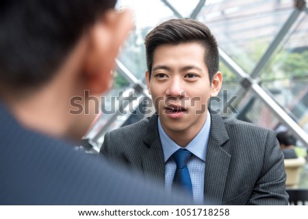 Young handsome Asian Chinese businessman talking to his partner with eye contact at office lounge Royalty-Free Stock Photo #1051718258