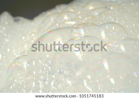 Abstract blurred bubbles white foam of washing powder on black background. Royalty-Free Stock Photo #1051745183