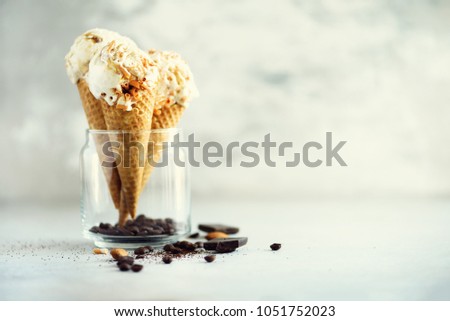 Caramel sauce ice cream in waffle cone with coffee beans on grey stone background. Summer food concept, copy space. Healthy gluten free ice-cream. Banner.