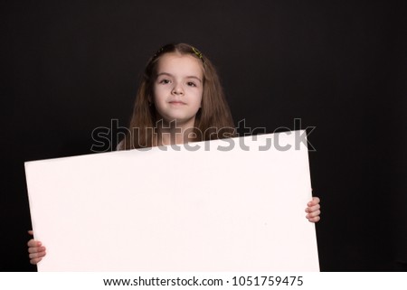 a caucasian girl holding a blank space for your advertisement. shooting in studio on a black background