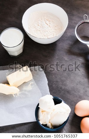 Baking ingredients, preparing dough on dark background from above. Copy space, vertical