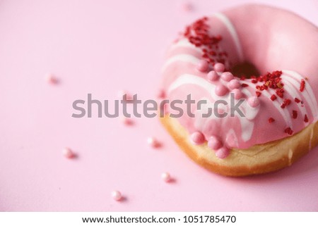 Sweet doughnut with pink icing on pastel background. Tasty donut on pink texture, copy space, top view.