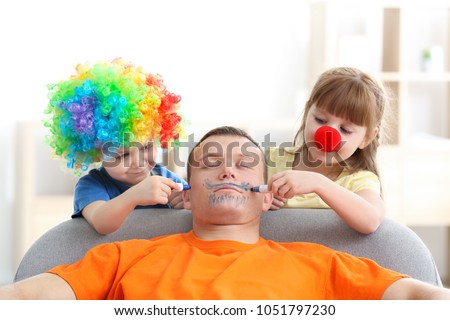 Little children painting their father's face while he sleeping. April fool's day prank Royalty-Free Stock Photo #1051797230