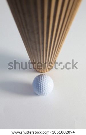 Corrugated brown paper roll and golf ball on the white desk. Exclamation mark.