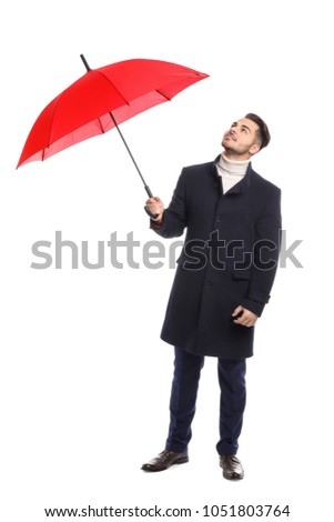 Young man in warm coat with red umbrella on white background