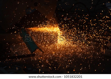 Electronic steel saw machine with glowing flow of spark in the dark, selective focus