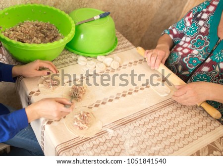 Woman and daughter rolls out dough in the kitchen
