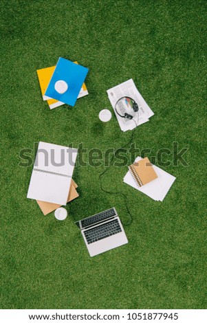 Heap of business objects and office supplies laying on green grass carpet 